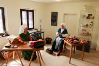 Zwei mittelalterlich gekleidete Frauen sitzen in einem Nähzimmer
